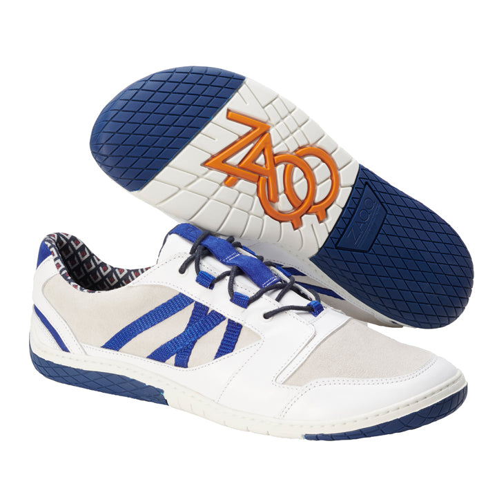 Wir präsentieren den QENDRIQ White von ZAQQ: Diese stylischen Sneaker haben ein weißes Obermaterial mit blauen Details und Akzenten aus Veloursleder. Sie zeichnen sich durch ein einzigartiges geometrisches Muster auf der Sohle und blaue Schnürsenkel aus. Die Unterseite ist mit einem runden orangefarbenen Logo mit den Buchstaben ZAO verziert, das für einen zusätzlichen Hauch von Eleganz sorgt.