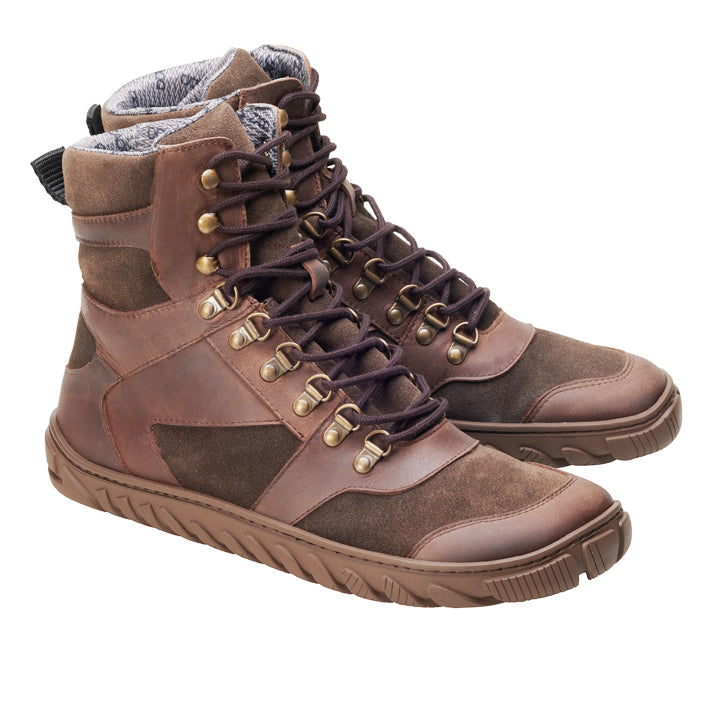 Die wasserdichten EXPLORER Brown-Stiefel von ZAQQ sind hohe Wanderstiefel aus Leder mit Wildlederakzenten, Metallösen und schwarzen Schnürsenkeln. Sie verfügen über eine dicke Gummisohle für hervorragenden Halt und ein gepolstertes Innenfutter, alles auf weißem Hintergrund.