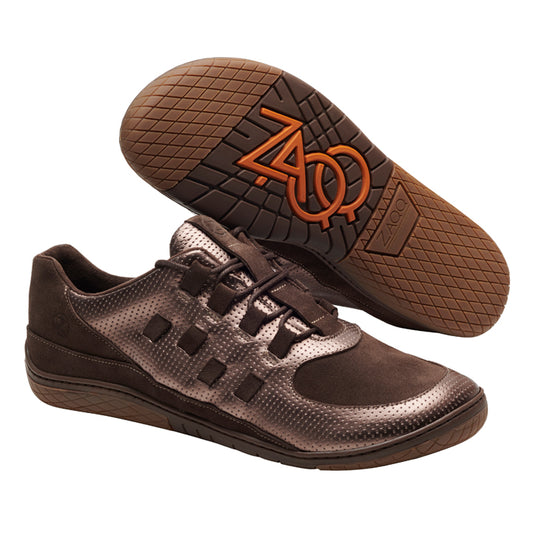 Ein modisches Paar BRISQ Bronze-Sneaker von ZAQQ in Dunkelbraun mit strukturierten Oberflächen und auffälligem BRISQ Bronze-Branding auf der Minimal Sohle. Diese Schuhe haben ein Schnürdesign und auffällige Nähte, wobei ein Schuh aufrecht steht und der andere seine markante braune Sohle hervorhebt.