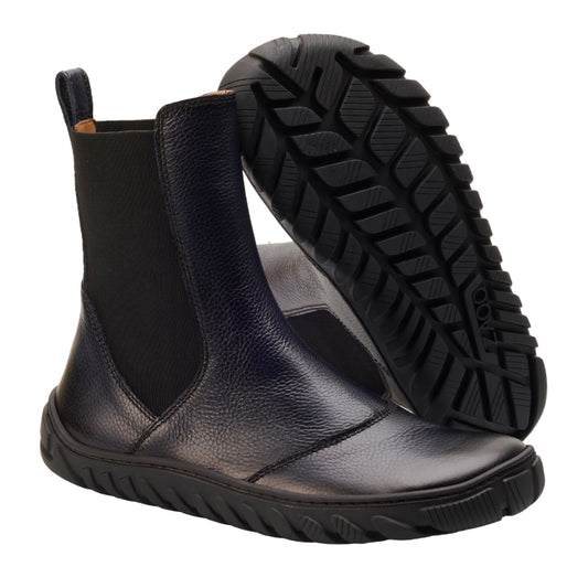 Wir präsentieren den ELASTIQ Blue von ZAQQ: Ein Paar elegante schwarze Chelsea-Boots aus Premium-Nappaleder, ausgestattet mit ULTRAGRIP-Sohle für hervorragende Traktion. Vor einem weißen Hintergrund steht ein Boot aufrecht, während der andere geneigt ist, um sein robustes Sohlenmuster hervorzuheben, ideal für jeden stilvollen Anlass.