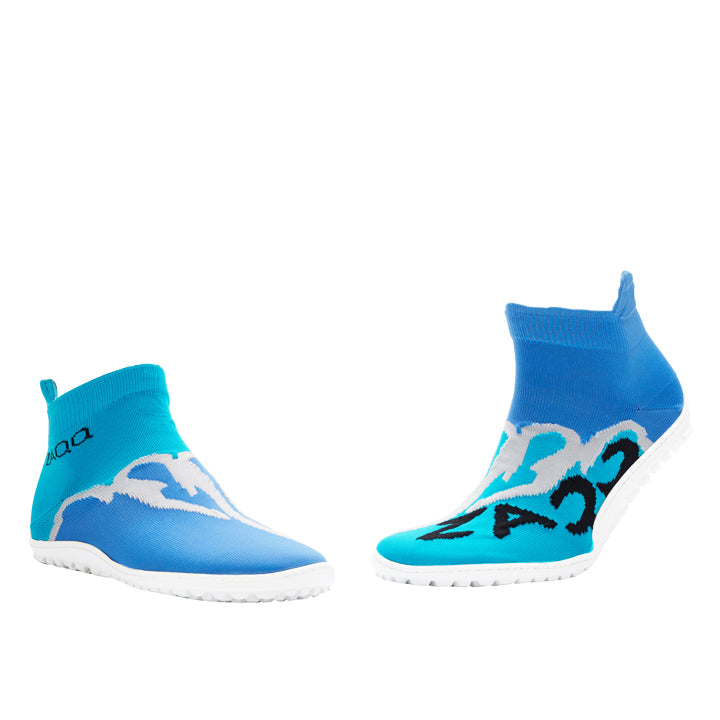 Ein Paar SOQQ Fire Blue Wasserschuhe von ZAQQ, beide mit Meereswellen-Design und weißen Sohlen. Der linke Schuh hat einen hohen Knöchelkragen mit dem Wort AQUA darauf, was seinen stilvollen Barfußschuh-Stil unterstreicht. Der rechte Schuh spiegelt das Design wider, weist aber zusätzliche schwarze Details auf. Sie werden nebeneinander angezeigt.