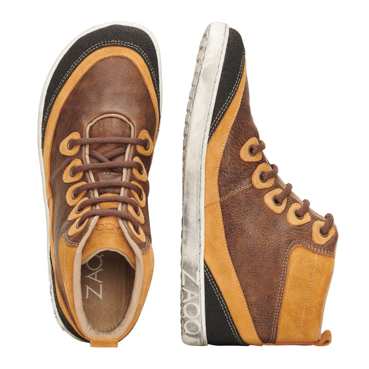 Die FRANQY Brown High-Top-Sneaker bieten außergewöhnlichen Tragekomfort mit ihrem stilvollen braun-braunen Design und den weißen Sohlen. Ein Schuh ist von oben zu sehen, während der andere den Markennamen ZAQQ an der Seite der Sohle zeigt. Diese Barfußschuhe sind zum Schnüren mit braunen Schnürsenkeln ausgestattet.