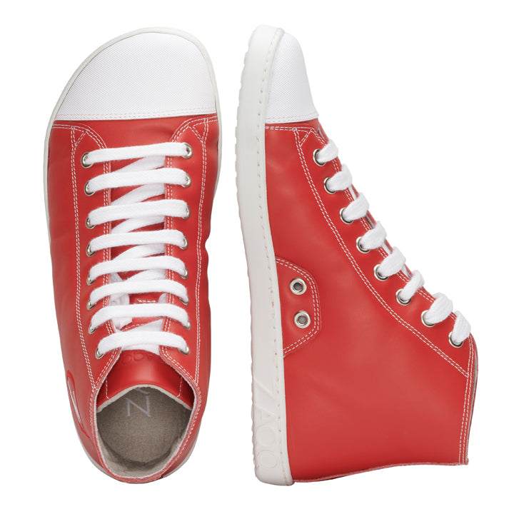 Wir präsentieren die CHUQQS Red Sneaker von ZAQQ mit einem auffälligen Design aus rotem Nappaleder, weißen Sohlen und passenden Schnürsenkeln. Ein Schuh steht aufrecht und zeigt seine mit metallischen Ösen verzierte Seite, während sein Partner flach liegt und die Draufsicht zeigt. Diese eleganten und modernen Sneaker sind ideal für jeden Anlass.