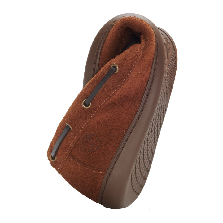 Der ZAQQ QEA Velours Cognac ist ein brauner Wildleder-Slipper mit Lederakzenten, der in einer stehenden Position präsentiert wird, die seine profilierte Gummisohle hervorhebt. Dieses Design bietet eine Mokassin-Ästhetik mit Metallösen und Nähten und verbindet nahtlos Eleganz und lässigen Komfort.