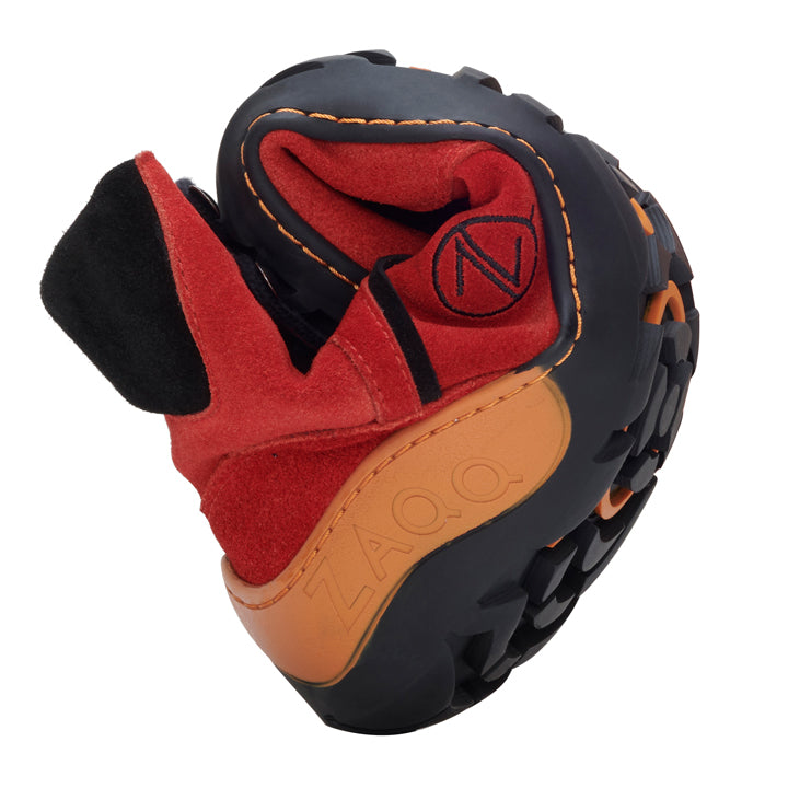 Der TERRAQ Orange Waterproof von ZAQQ ist ein vielseitiger Schuh in Schwarz- und Rottönen mit orangefarbenen Akzenten. Die Flexibilität des Schuhs zeigt sich in seinem gebogenen Design. Die strapazierfähige ZAQQ TERRA-Sohle sorgt für hervorragenden Halt und der Markenname ZAQQ ist deutlich auf der Seite zu sehen.