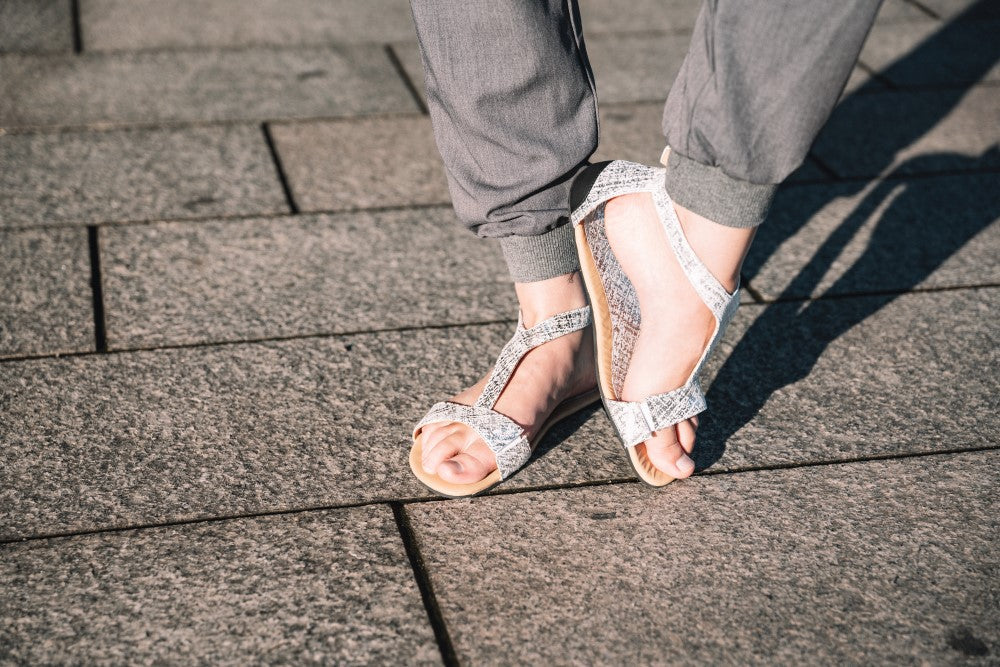 CLIQ Silver-Sandalen von ZAQQ mit silbernem Metallic-Finish, offenen Zehen, Knöchelriemen und einer Kautschuksohle auf weißem Hintergrund.