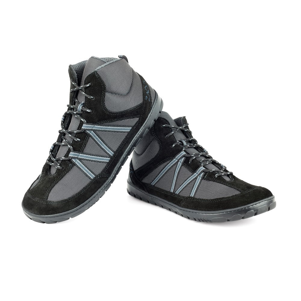 Der ROQQ Trail Black von ZAQQ ist ein Paar schwarz-graue High-Top-Wanderschuhe mit robuster Trailsohle und Schnürdesign. Gefertigt aus strapazierfähigem Meshgewebe ist ein Schuh leicht erhöht und lehnt sich an den anderen auf einem schlichten weißen Hintergrund.