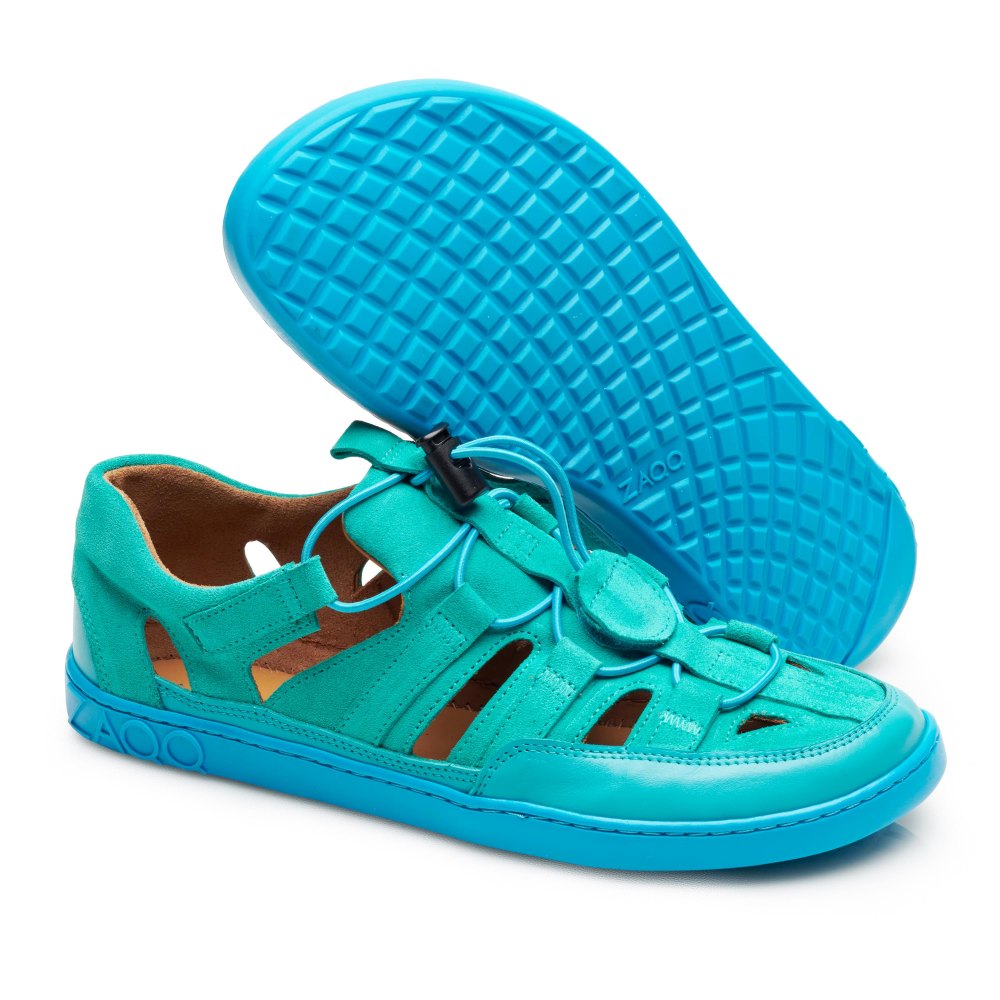 Die ZAQQ QLEAR Turquoise Sandalen zeichnen sich durch ein einzigartiges Design mit stilvollen Aussparungen an den Seiten und einer geschlossenen Spitze aus. Sie haben eine leuchtend blaue, strukturierte Sohle und einen Schnürverschluss. Die sichtbare Sohle einer Sandale weist ein Rautenmuster für besseren Halt auf.