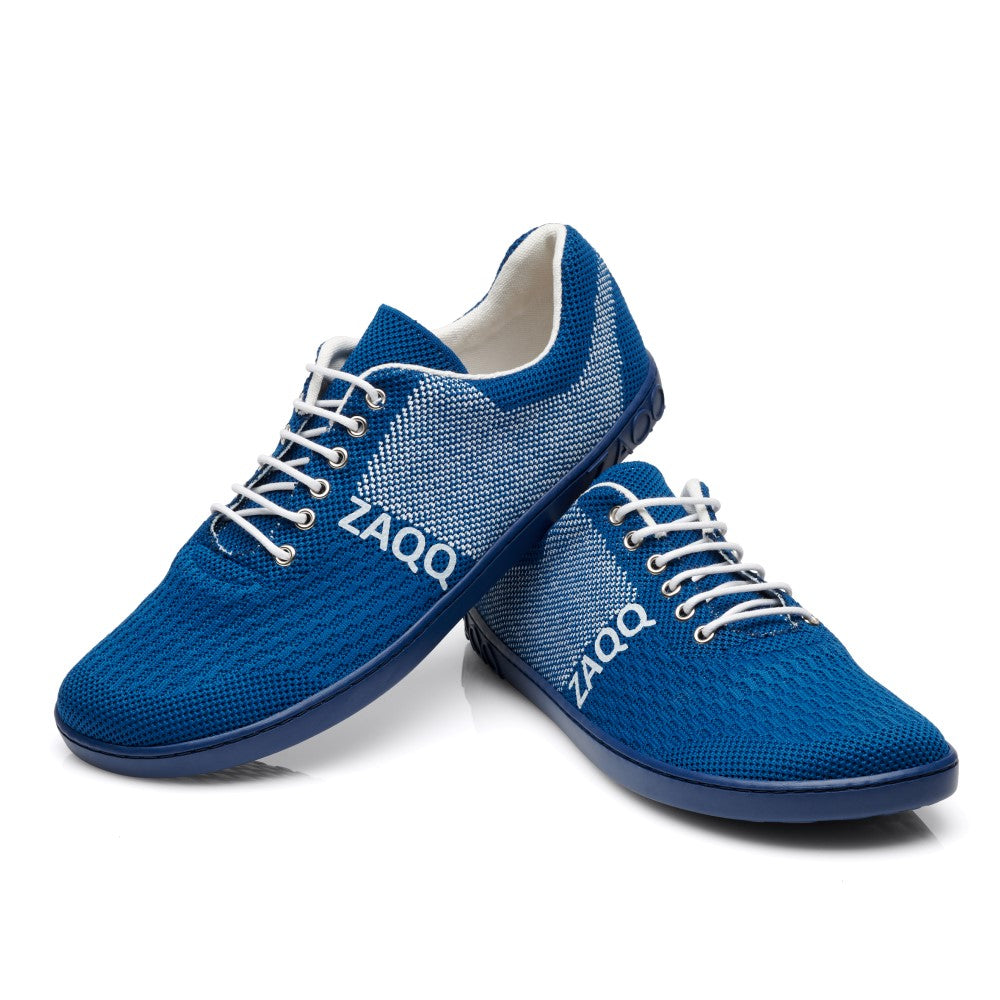 Ein Paar QNIT Mare Sneaker in Blau und Weiß, mit weißen Schnürsenkeln und einem strukturierten, atmungsaktiven Baumwollstrickdesign. Der Markenname ZAQQ ist seitlich auf jedem veganen Barfußschuh aufgedruckt. Ein Schuh steht aufrecht, während der andere daran lehnt.